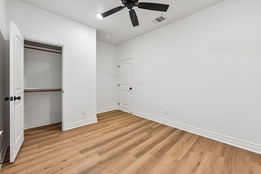 Blonde wood flooring grounds this naturally illuminated bedroom with a modern ceiling fan. Blonde wood flooring grounds this naturally illuminated bedroom with a modern ceiling fan.