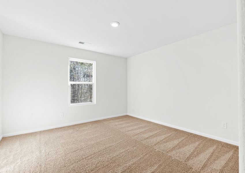 Secondary bedroom with tan carpet and a window.