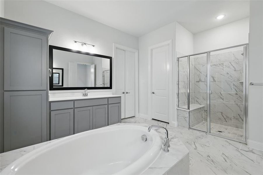Bathroom featuring a stall shower, a bath, baseboards, marble finish flooring, and vanity