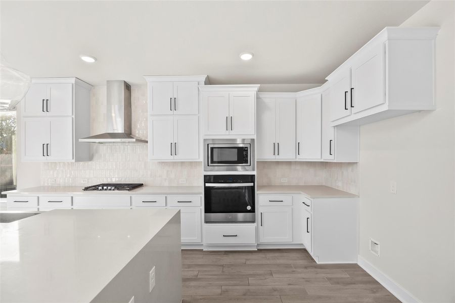 This modern kitchen features sleek white cabinetry, a built-in oven and microwave, and a stainless steel range hood. The spacious countertops and ample storage offer both functionality and style. This modern kitchen features sleek white cabinetry, a built-in oven and microwave, and a stainless steel range hood. The spacious countertops and ample storage offer both functionality and style.