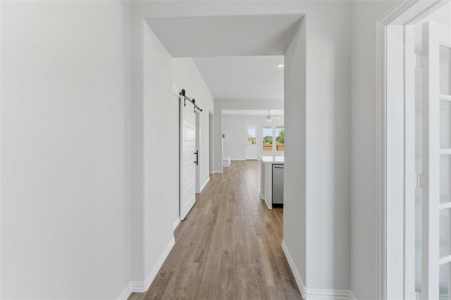 Hallway featuring a barn door, light wood-style flooring, and recessed lighting