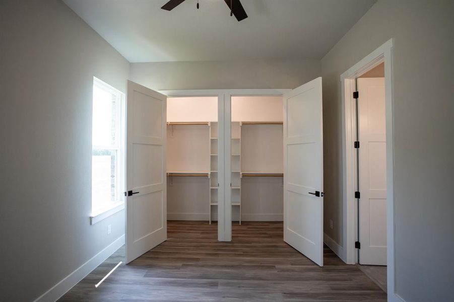 Unfurnished bedroom featuring multiple closets, dark wood-type flooring, and a ceiling fan Unfurnished bedroom featuring multiple closets, dark wood-type flooring, and a ceiling fan