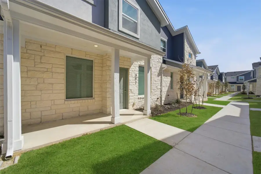 View of exterior entry featuring covered porch, a lawn, stone siding, stucco siding, and a residential view View of exterior entry featuring covered porch, a lawn, stone siding, stucco siding, and a residential view