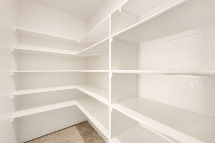 Walk-in pantry with white wrap-around shelving on three walls and tile floor