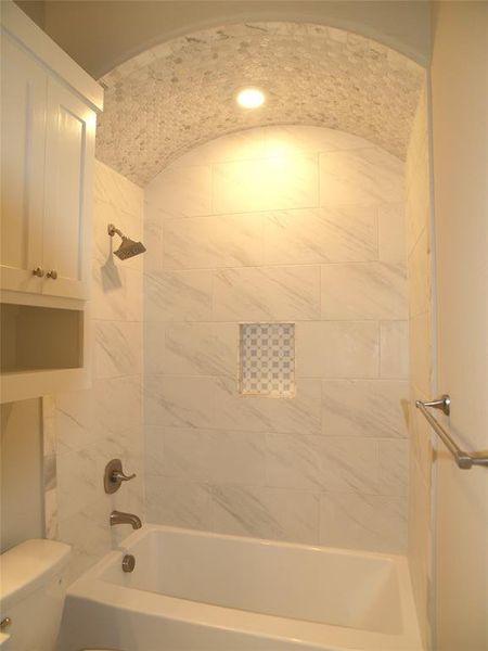 Bathroom featuring tiled shower / bath combo and toilet