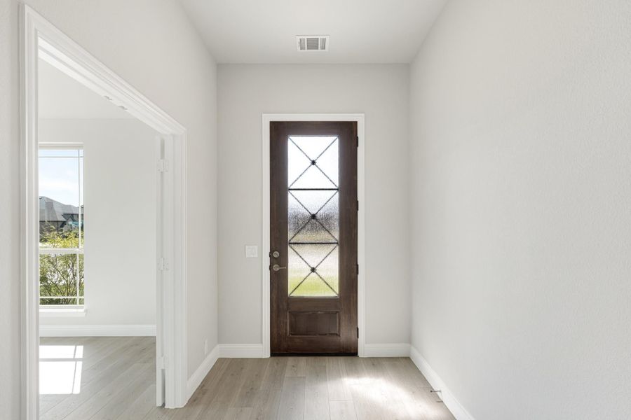 Entryway with dark wood front door featuring decorative glass panels and light hardwood floors