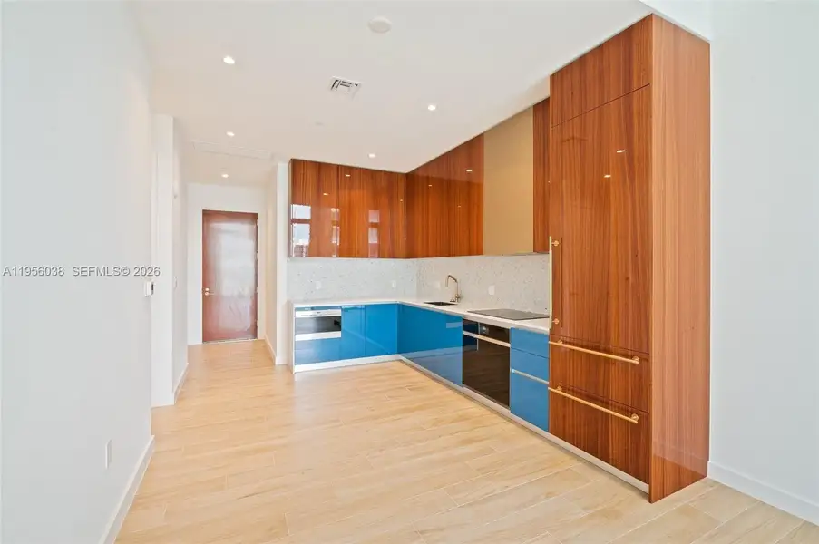 Gourmet kitchen with blue accent cabinetry, wood-paneled storage, brass hardware, and high-end finishes at Mr. C Residences.