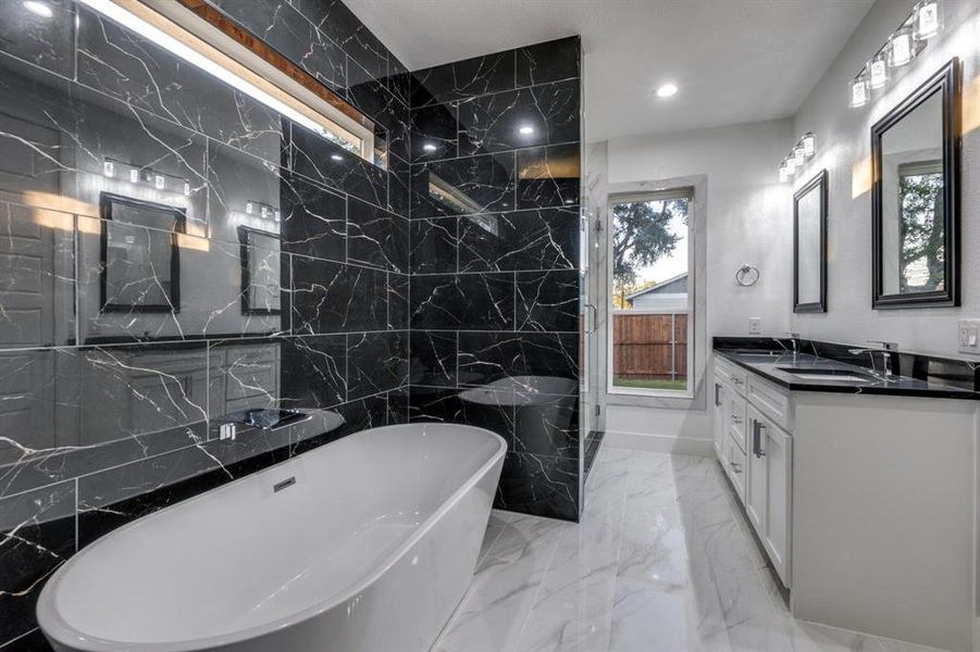 Bathroom featuring vanity, a healthy amount of sunlight, and a tub to relax in