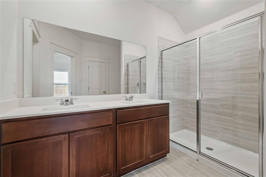 Bathroom with a stall shower, double vanity, and vaulted ceiling Bathroom with a stall shower, double vanity, and vaulted ceiling