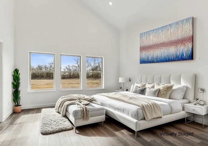 Bedroom with hardwood / wood-style flooring, a high ceiling, and multiple windows