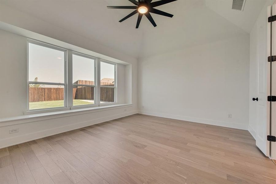 Empty room with light wood-style floors, lofted ceiling, and ceiling fan Empty room with light wood-style floors, lofted ceiling, and ceiling fan