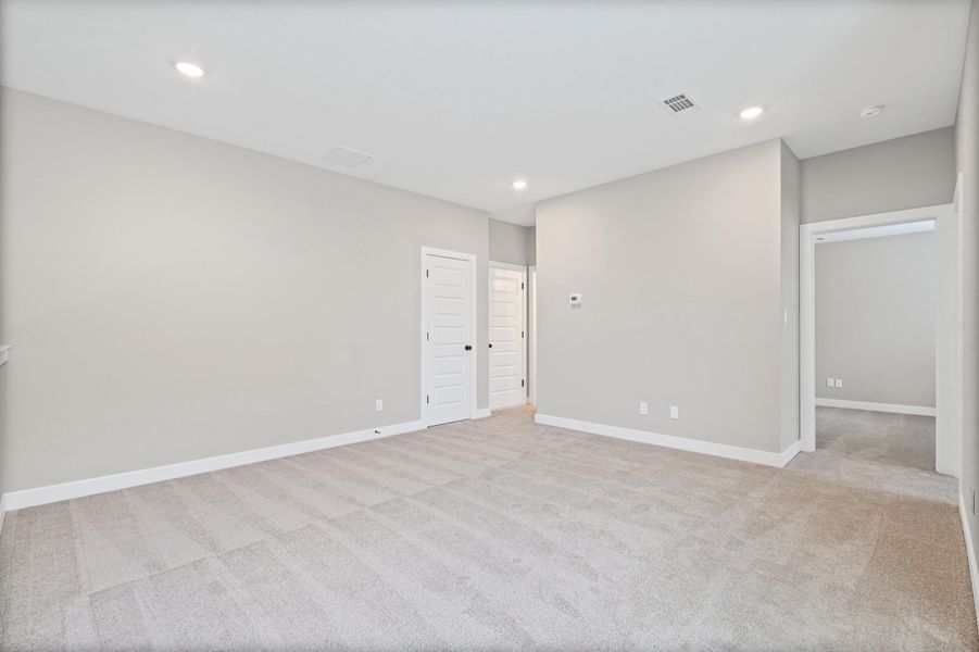 Expansive carpeted room featuring recessed lighting, white baseboards, and neutral wall tones Expansive carpeted room featuring recessed lighting, white baseboards, and neutral wall tones