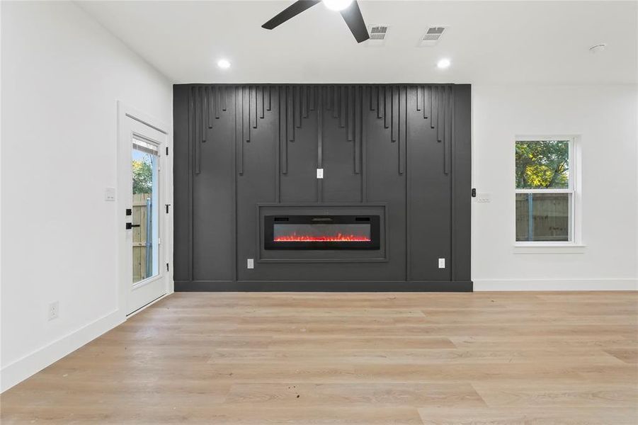 Detailed view of a glass covered fireplace, wood finished floors, recessed lighting, and a ceiling fan Detailed view of a glass covered fireplace, wood finished floors, recessed lighting, and a ceiling fan