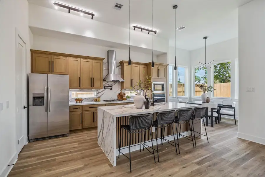 Fully equipped kitchen features stainless steel appliances, large kitchen island with waterfall quartz, gas cooktop, modern finishes and tons of natural lighting