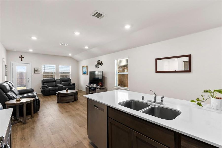 Kitchen featuring lofted ceiling, light wood-style flooring, dark wood finish cabinetry, recessed lighting, and healthy amount of natural light Kitchen featuring lofted ceiling, light wood-style flooring, dark wood finish cabinetry, recessed lighting, and healthy amount of natural light