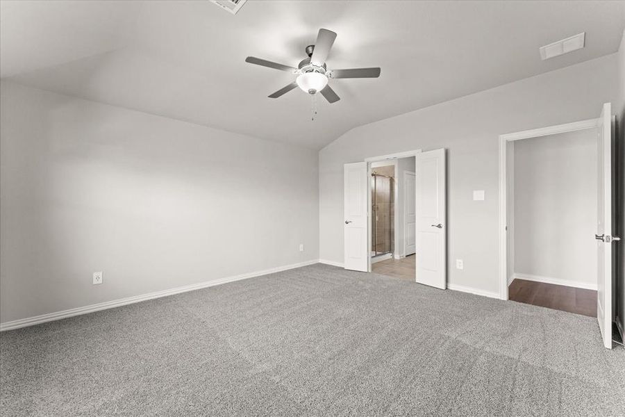 Unfurnished bedroom featuring ceiling fan, lofted ceiling, and carpet