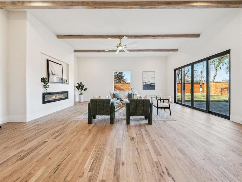 Living room with ceiling fan, light hardwood / wood-style flooring, and beamed ceiling