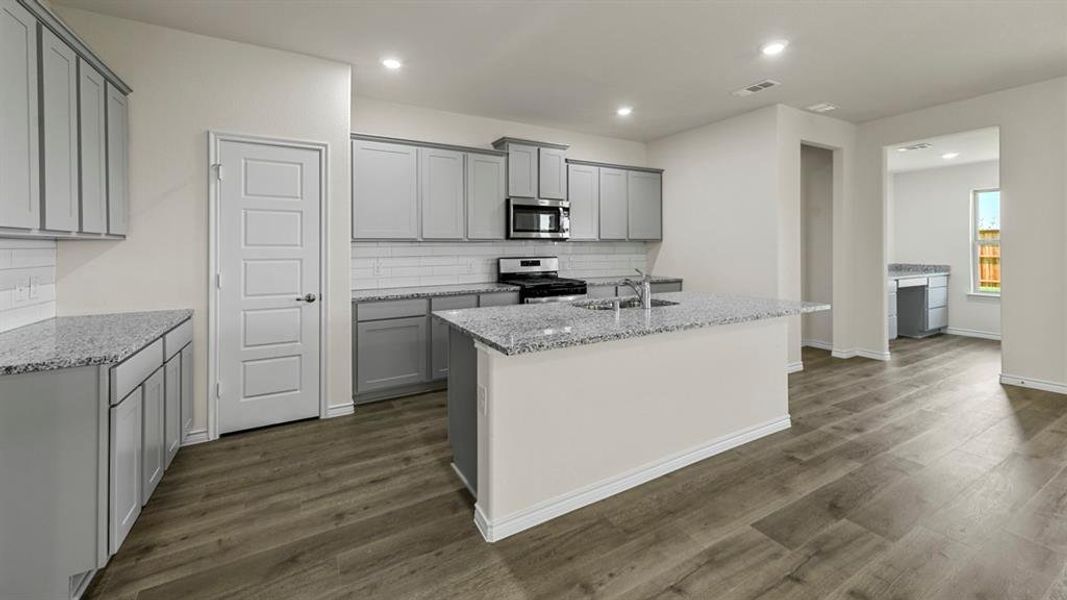 The kitchen features grey cabinetry, granite countertops, a tile backsplash, and stainless steel appliances