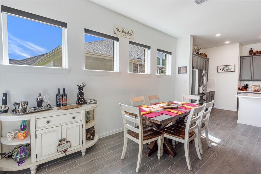 Bright and inviting dining space with modern wood-look tile flooring, ample natural light from multiple windows, all in this open space concept.