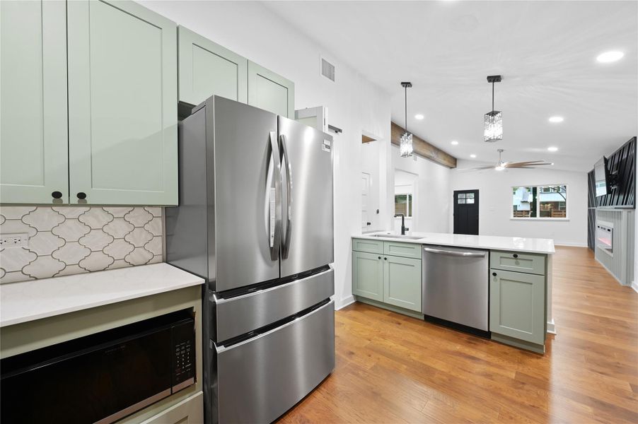 Kitchen featuring stainless steel appliances, a sink, a peninsula, green cabinets, and ceiling fan