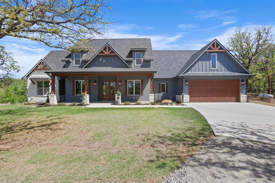 Craftsman inspired home featuring board and batten siding, roof with shingles, a front lawn, french doors, and driveway
