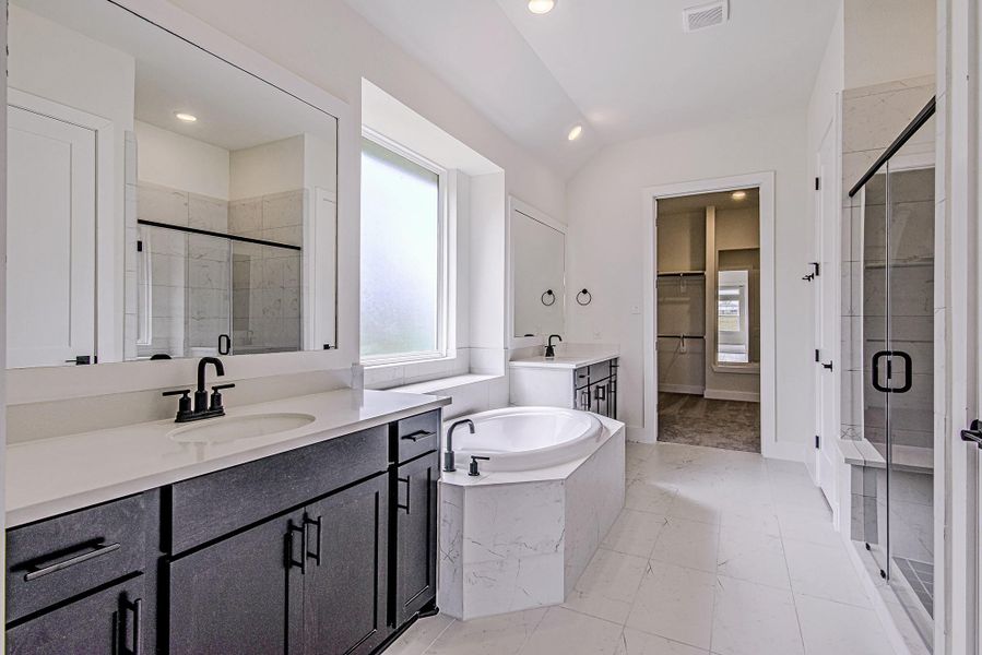 The luxurious primary bathroom features dual vanities, a soaking tub, and a separate walk-in shower The luxurious primary bathroom features dual vanities, a soaking tub, and a separate walk-in shower
