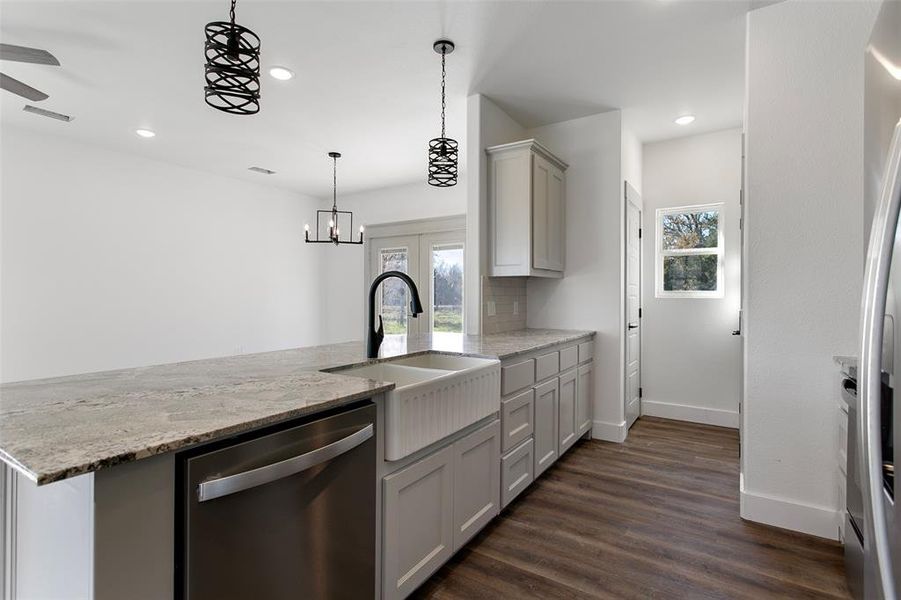 Kitchen featuring gray cabinetry, dishwasher, sink, dark hardwood / wood-style floors, and light stone counters