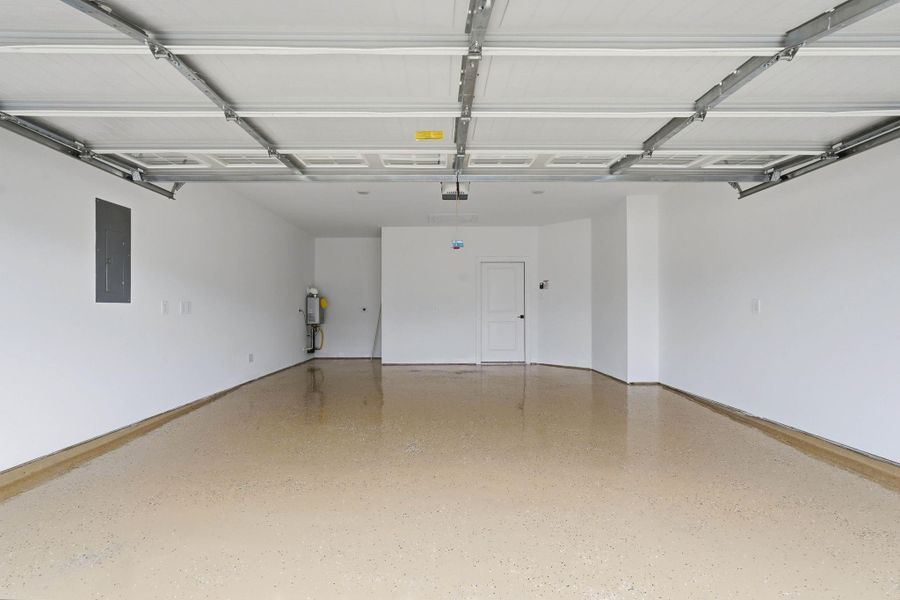The spacious garage, featuring a polished floor, offers plenty of room for parking, storage, or projects.