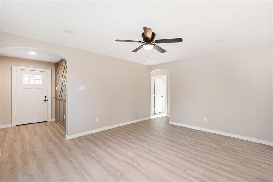 Spare room featuring arched walkways, light wood-style floors, and ceiling fan