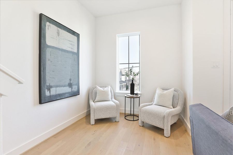 This inviting nook offers a cozy and sophisticated space to relax and unwind. Bathed in natural light from a sleek, modern window. The neutral palette and light wood flooring create a serene and welcoming atmosphere, perfect for a morning coffee or a quiet moment of reflection.
