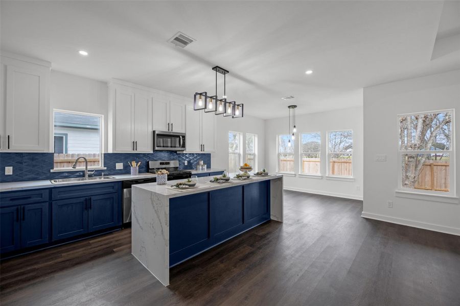 Sleek navy and white cabinetry, a central island with elegant marble-like countertops, and chic pendant lighting. Large windows provide ample natural light, and the open layout flows seamlessly into a dining area, perfect for entertaining. Sleek navy and white cabinetry, a central island with elegant marble-like countertops, and chic pendant lighting. Large windows provide ample natural light, and the open layout flows seamlessly into a dining area, perfect for entertaining.