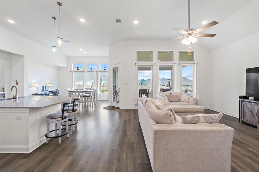 Enjoy an open-concept living area defined by soaring ceilings and warm wood-plank flooring.