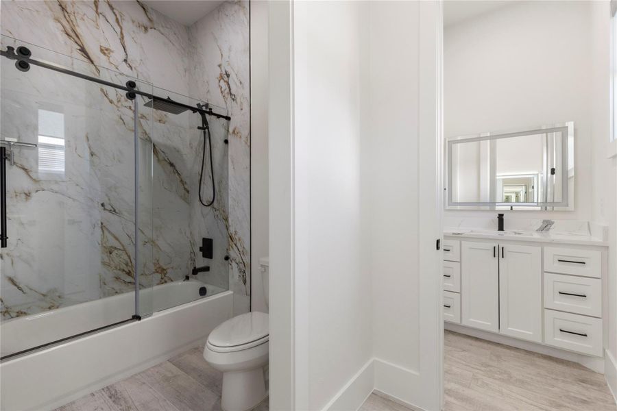 Jack and Jill bathroom with separate vanities and a tub-shower combo with a sliding glass door and a large rain showerhead. Jack and Jill bathroom with separate vanities and a tub-shower combo with a sliding glass door and a large rain showerhead.