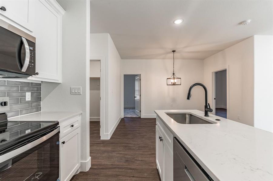 Kitchen with pendant lighting, sink, white cabinets, and stainless steel electric range oven