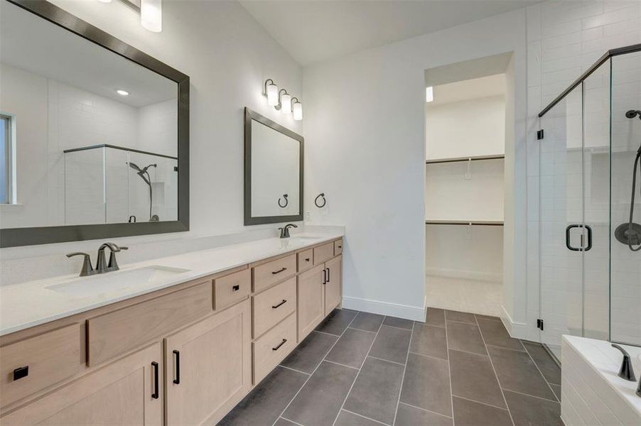 Dual vanity with light wood cabinetry, white countertops, and dark framed mirrors Dual vanity with light wood cabinetry, white countertops, and dark framed mirrors