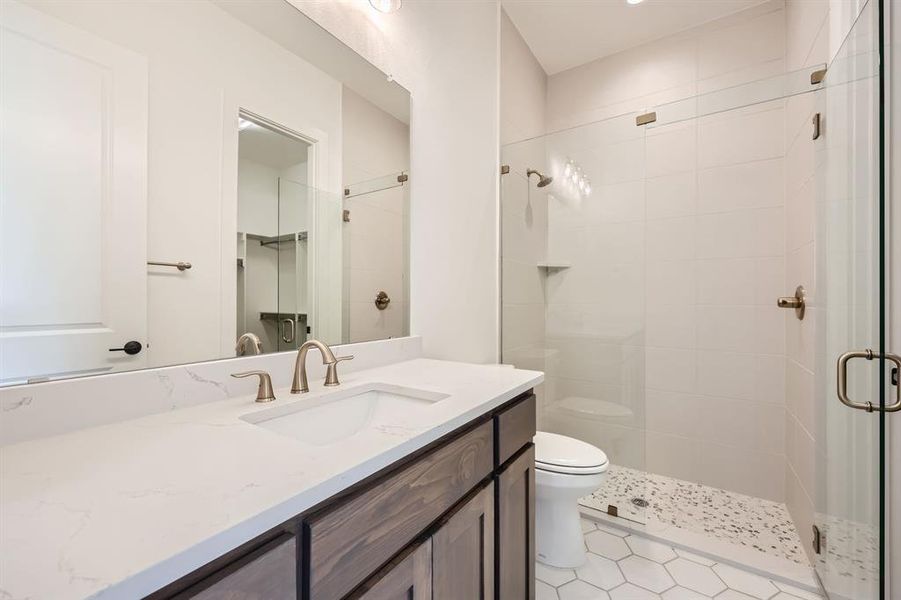 Bathroom featuring vanity, toilet, tile patterned floors, and a shower with door