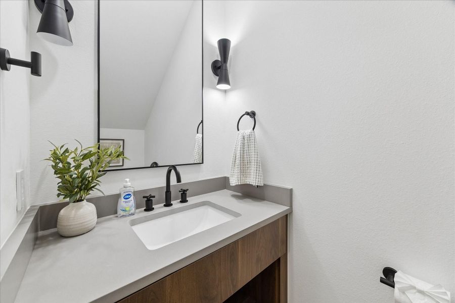Floating walnut vanity, quartz countertop, matte black fixtures, and minimalist lighting deliver a refined designer powder room.