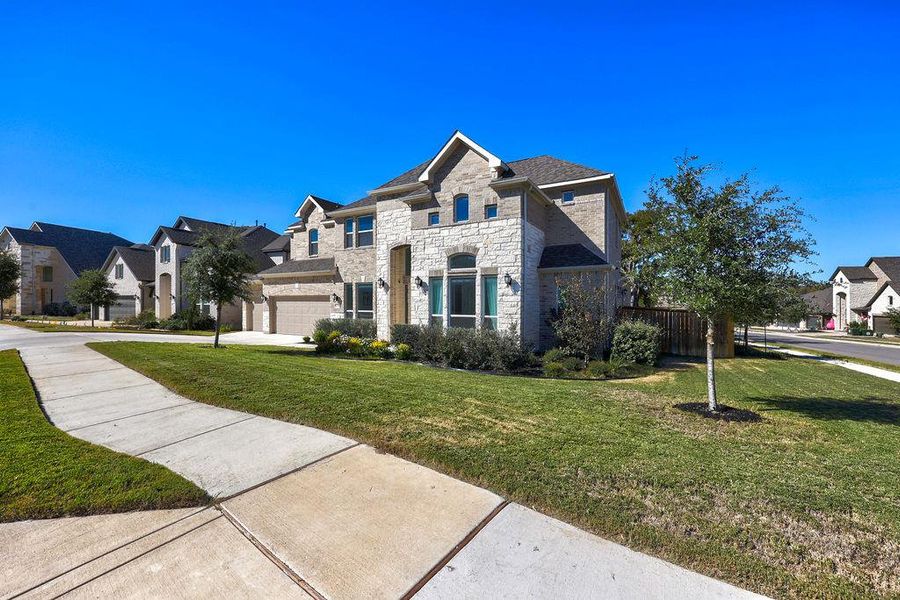 French country home with stone siding, a residential view, and concrete driveway