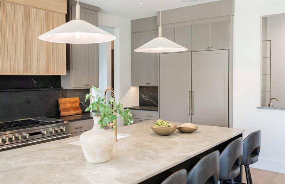 Kitchen with gray cabinetry, pendant lighting, light stone countertops, and tasteful backsplash