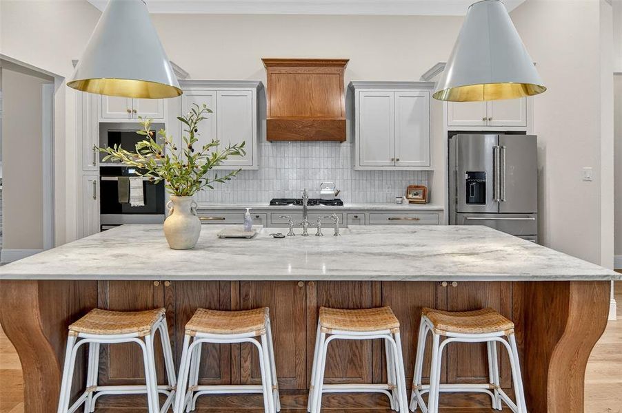 Kitchen with tasteful backsplash, stainless steel appliances, light wood finished floors, and a kitchen breakfast bar