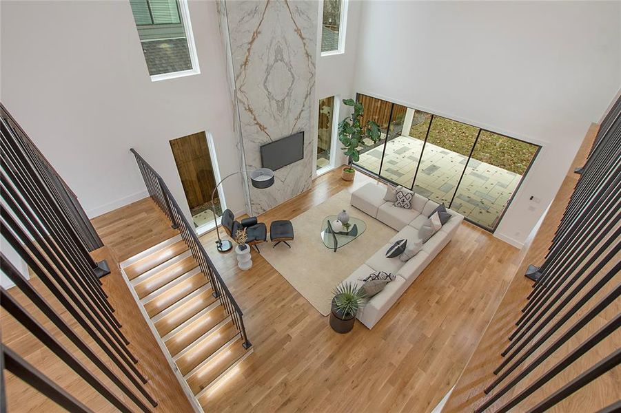 Living room featuring a wealth of natural light, wood-type flooring, a fireplace, and a towering ceiling