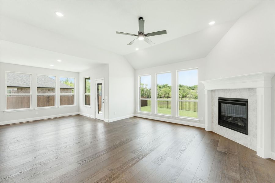 Open living room with vaulted ceiling, hardwood floors, ceiling fan, and marble fireplace surround Open living room with vaulted ceiling, hardwood floors, ceiling fan, and marble fireplace surround
