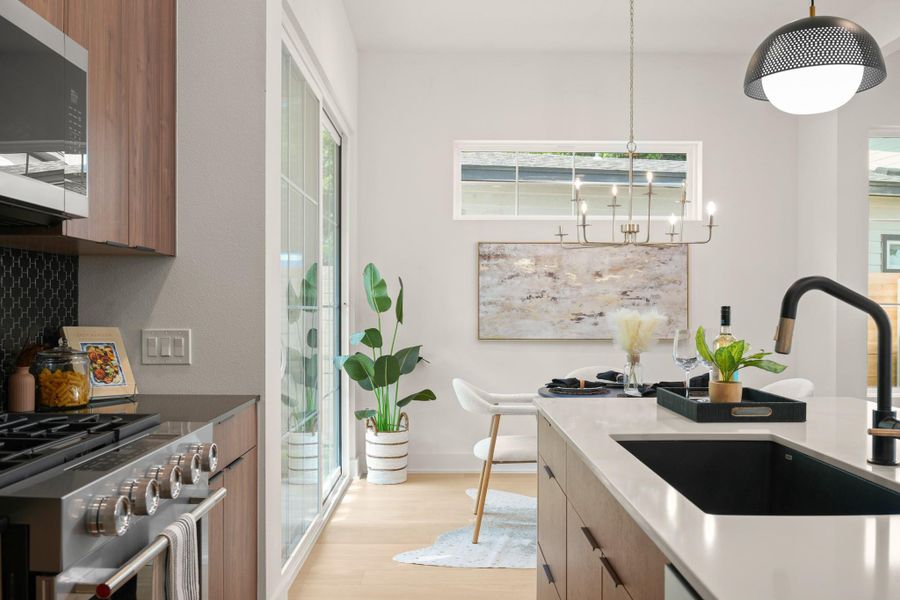 Culinary adventures await in this modern kitchen, boasting an island with a sleek sink and a dining area illuminated by elegant chandeliers. Culinary adventures await in this modern kitchen, boasting an island with a sleek sink and a dining area illuminated by elegant chandeliers.