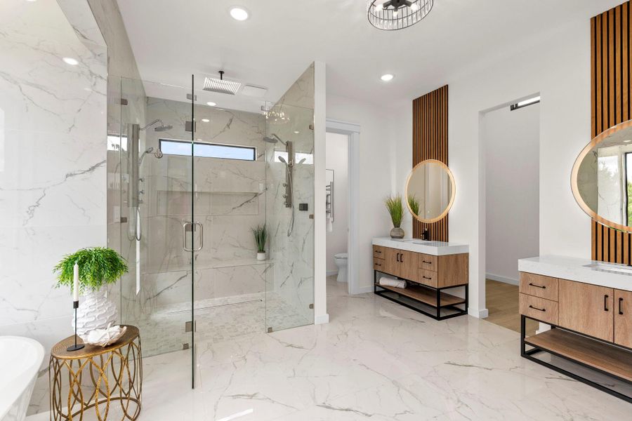 Full bathroom with a marble finish shower, a freestanding tub, two vanities, recessed lighting, and light marble finish floors