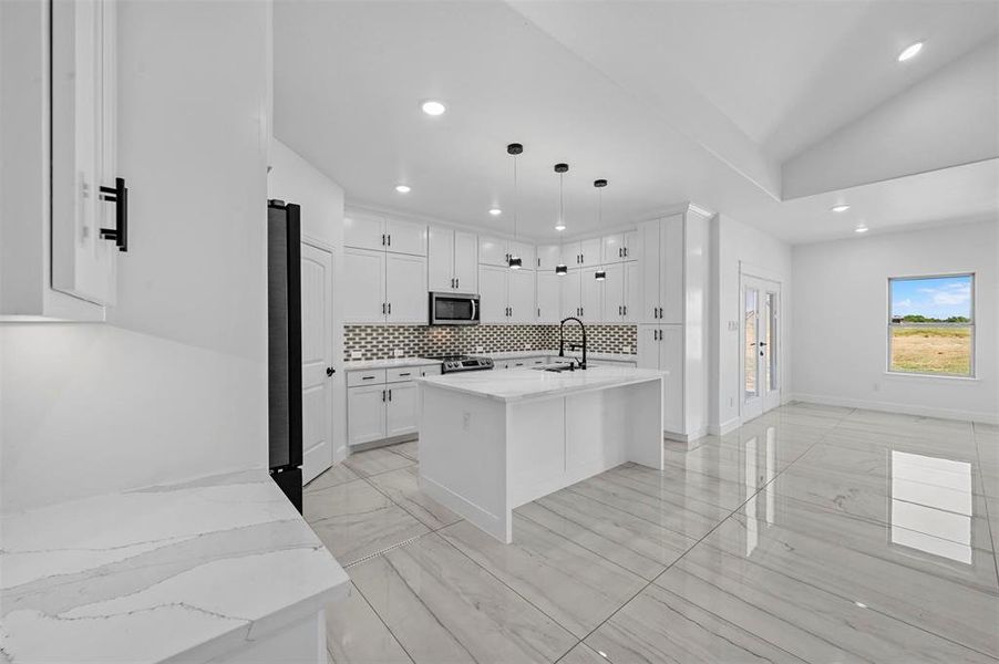 Kitchen with white cabinets, appliances with stainless steel finishes, sink, pendant lighting, and tasteful backsplash