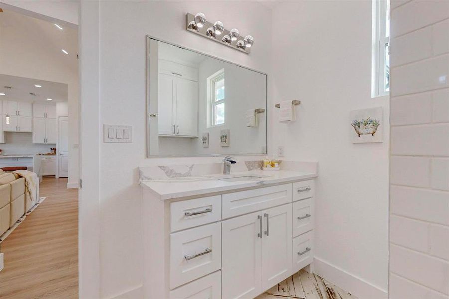 Bathroom with plenty of natural light, vaulted ceiling, vanity, and hardwood / wood-style flooring