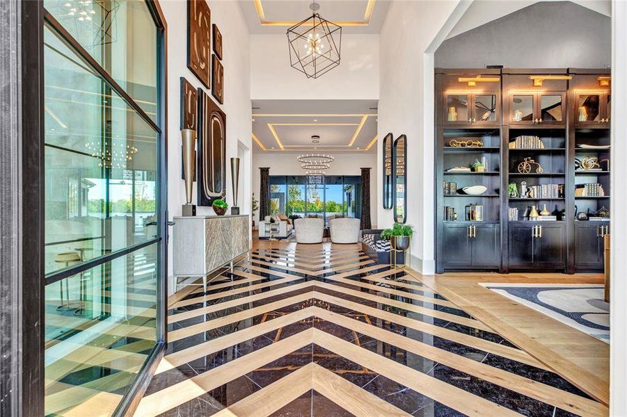 Entryway with a chandelier, inlaid floor details, a towering ceiling, and a tray ceiling Entryway with a chandelier, inlaid floor details, a towering ceiling, and a tray ceiling