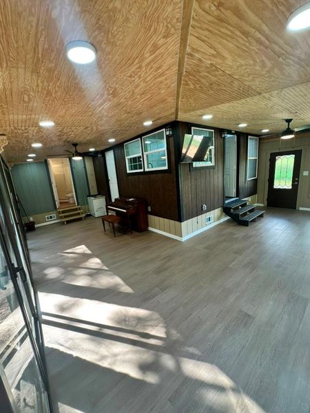 Natural light illuminates the spacious, newly floored interior with unique wood paneling.