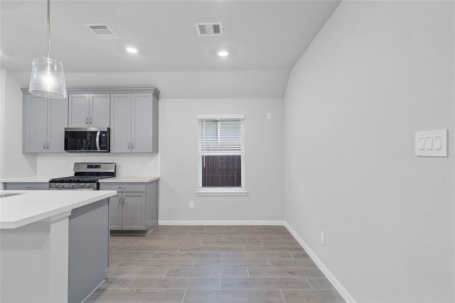 Enjoy meals in this sun-drenched space, featuring durable tile flooring, abundant natural light from the large windows (fitted with blinds), and recessed lighting.