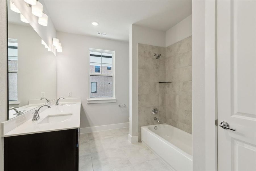 Secondary Bathroom featuring double vanity, tub / shower combination, a sink, and baseboards